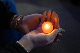 An attendee of the vigil holds a candle in their hands. Everyone who attended was given a battery-powered candle.